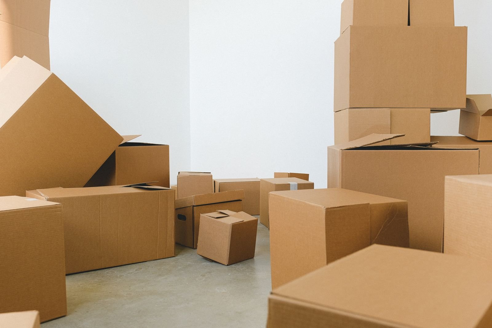 Cartons de tailles diverses posés au sol d'une pièce vide, conditionnement adapté à l'évacuation par navettes dans une rue étroite