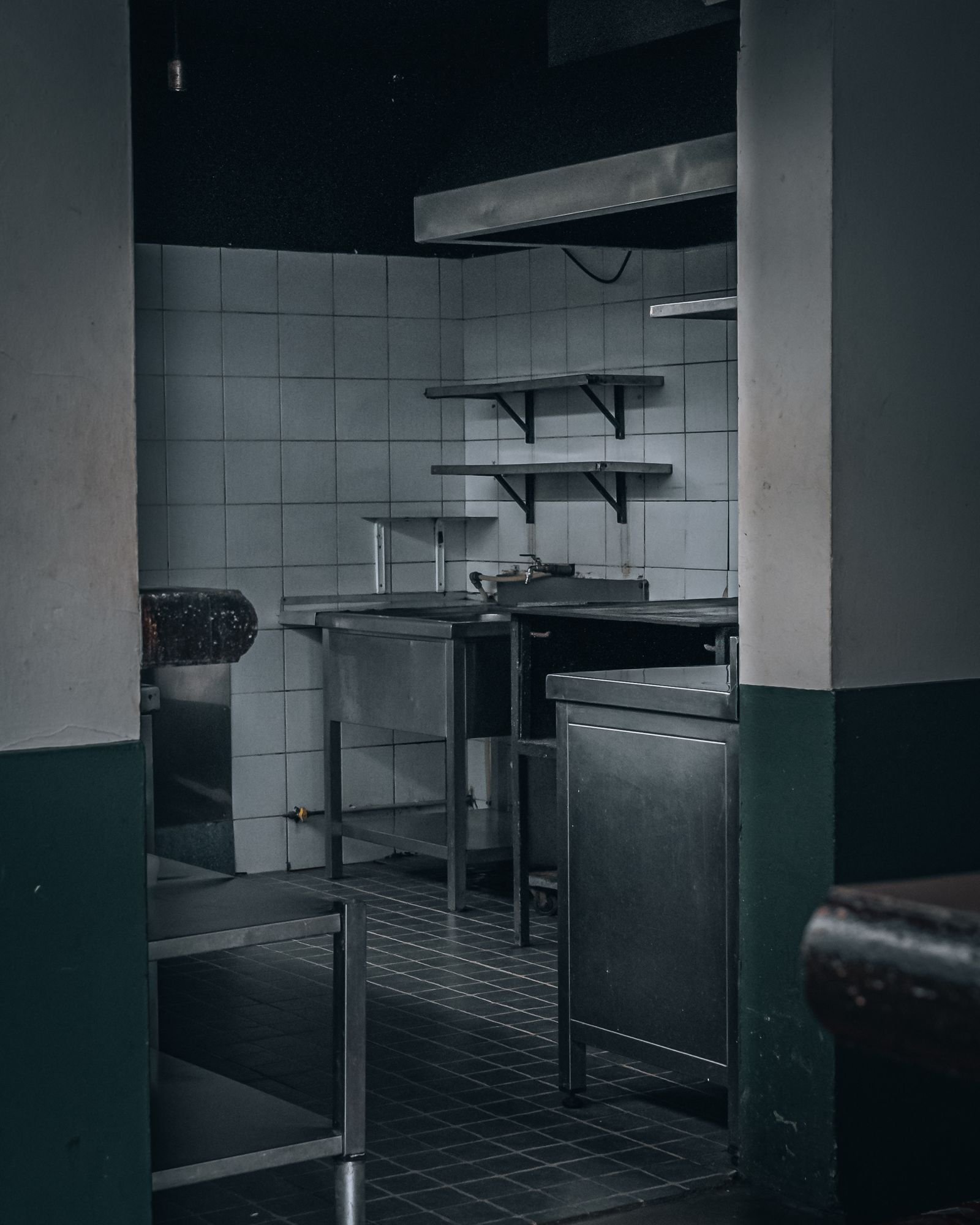 Cuisine professionnelle sombre et à l'arrêt, équipements inox en place, telle qu'on la retrouve à la fermeture de saison d'un établissement varois